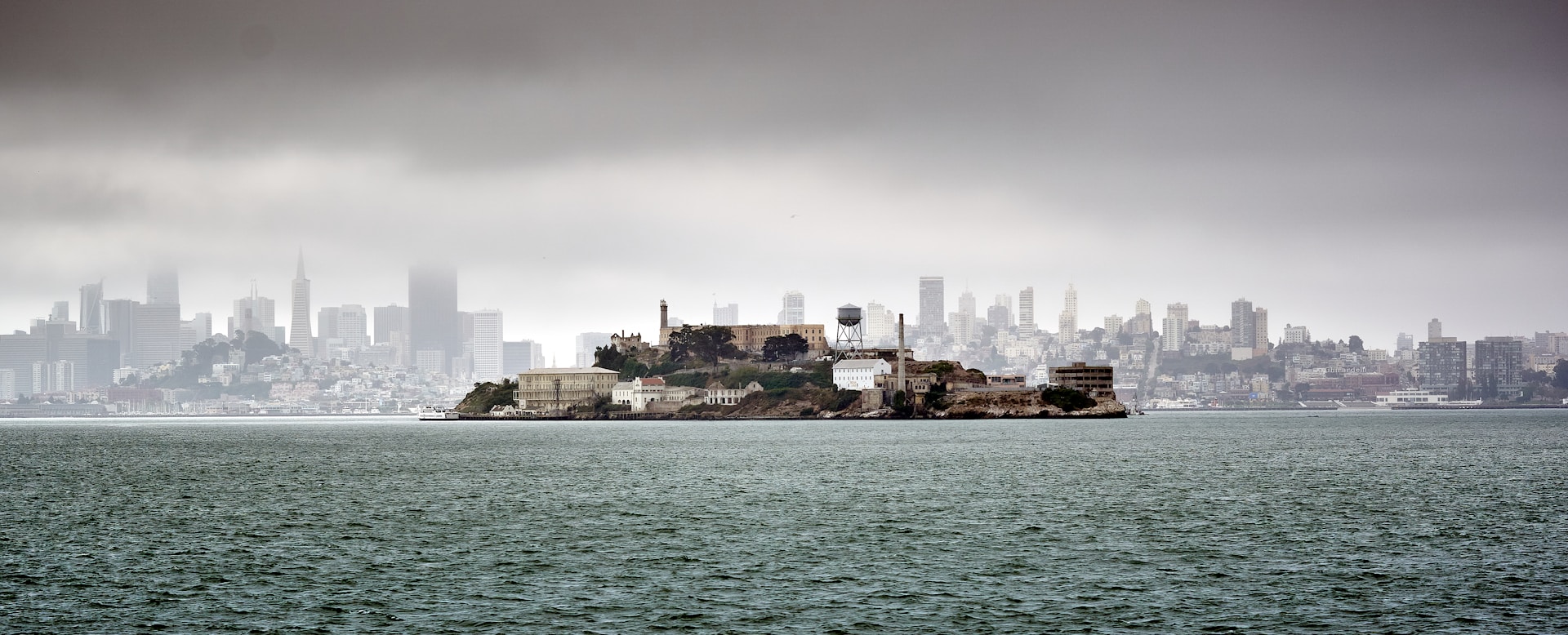 Photo of Alcatraz Island with San Francisco shrouded in fog in the background.